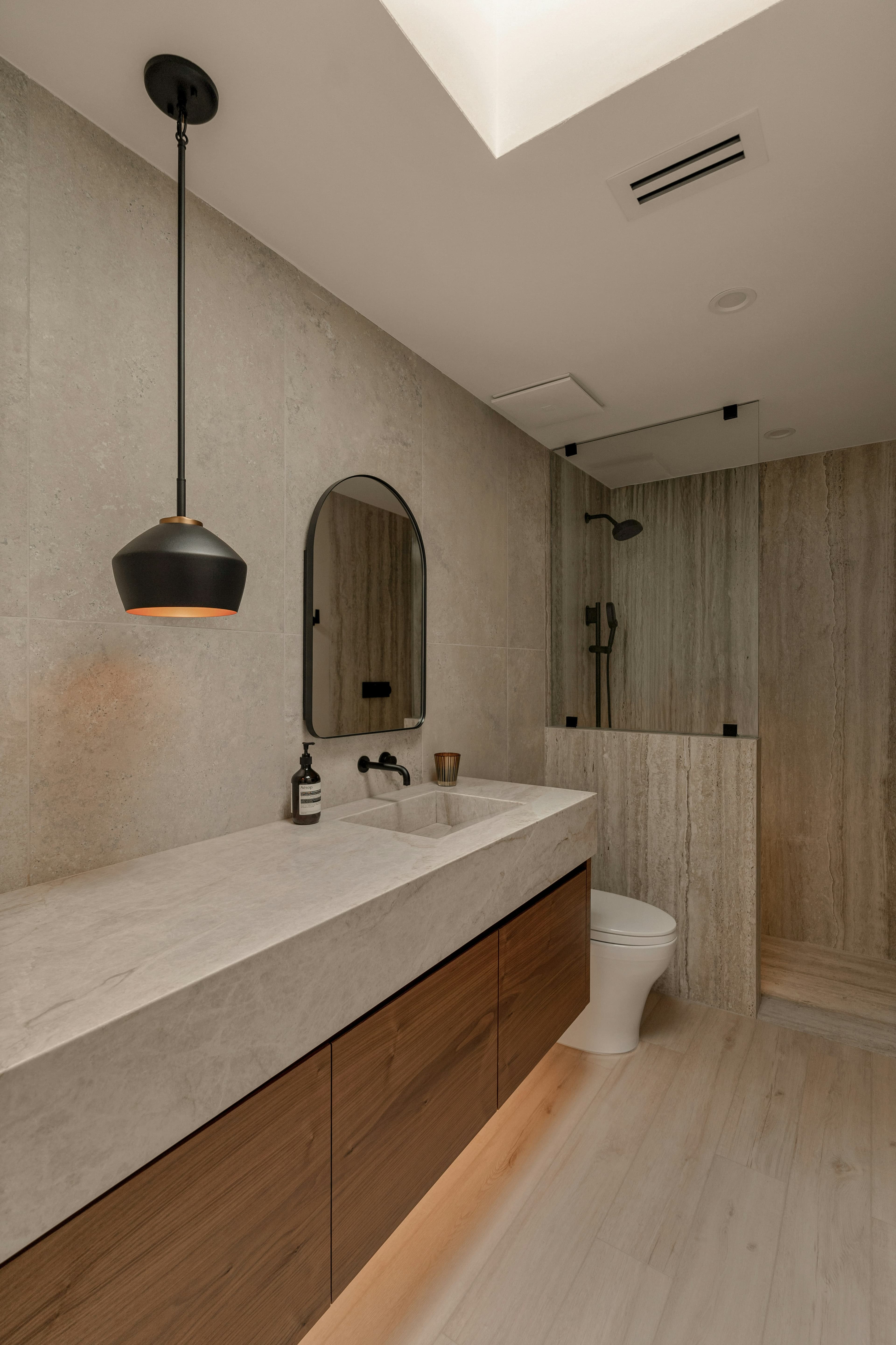 Wood vanity with a pale countertop and stone tiles